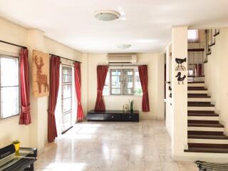 Bright and spacious living room with large windows and staircase