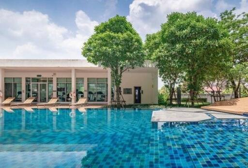 Outdoor pool area with a modern building and lush trees