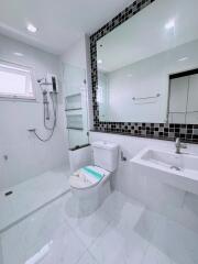 Modern bathroom with glass shower, large mirror, and white fixtures