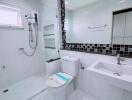 Modern bathroom with glass shower, large mirror, and white fixtures