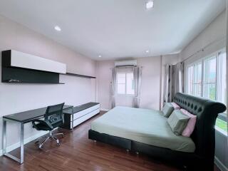 Spacious bedroom with large windows, desk area, and king-sized bed