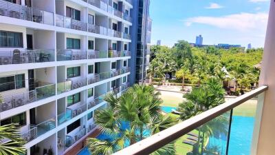 View of building with multiple balconies overlooking a swimming pool and greenery