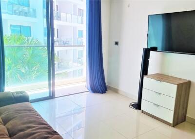 Modern living room with a sofa, flat-screen TV, and balcony view