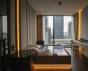 Modern bedroom with bed, desk, and panoramic window view of cityscape