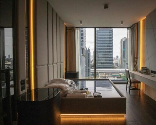 Modern bedroom with bed, desk, and panoramic window view of cityscape