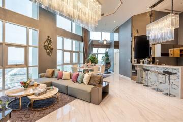 Modern and spacious living area with high ceilings, chandelier lighting, and large windows