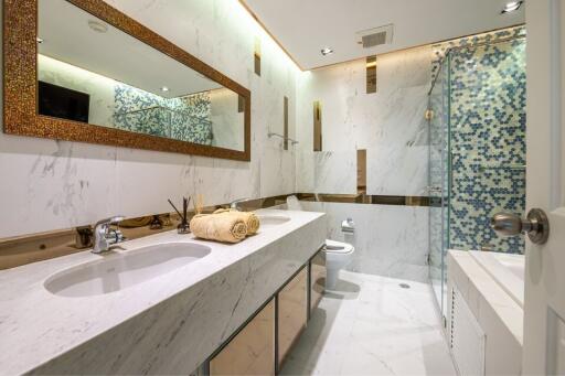 Modern bathroom with marble countertops, large mirror, and glass-enclosed shower