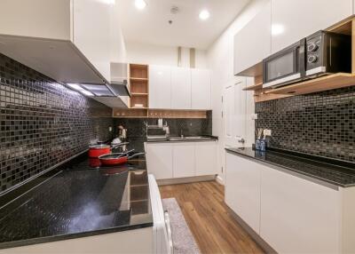 Modern kitchen with black tiled backsplash and white cabinetry