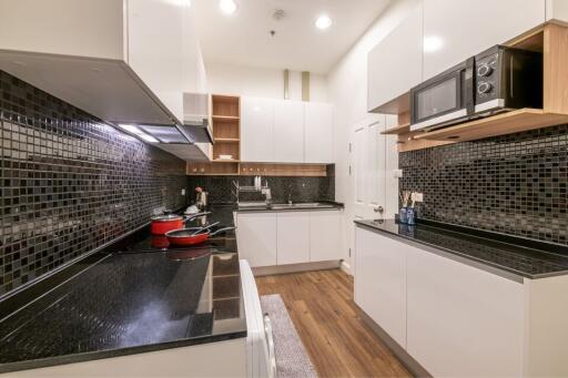 Modern kitchen with black tiled backsplash and white cabinetry