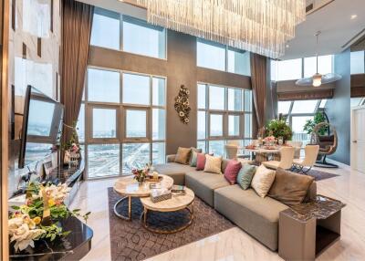 Spacious and luxurious living room with large windows, modern decor, and a high ceiling