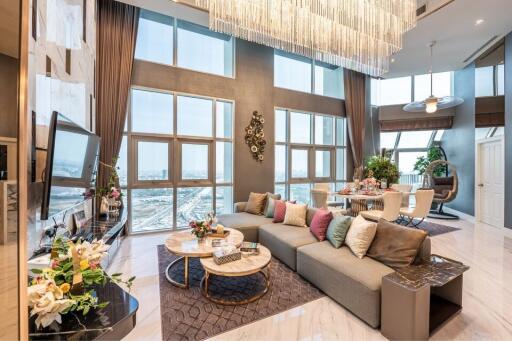 Spacious and luxurious living room with large windows, modern decor, and a high ceiling