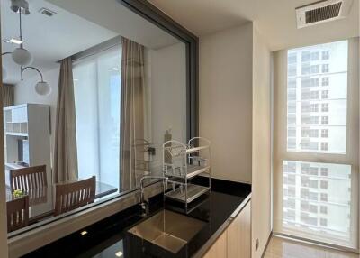 Modern kitchen with black countertop and window connecting to dining area