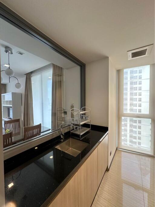 Modern kitchen with black countertop and window connecting to dining area