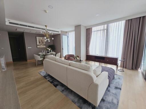 Modern living room with beige sofa, dining area, and large windows