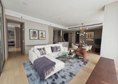 Modern living room with a white sectional sofa, glass coffee table, and an adjacent dining area