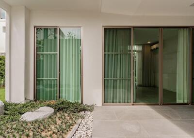 Modern exterior view with large sliding glass doors and greenery