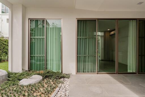 Modern exterior view with large sliding glass doors and greenery