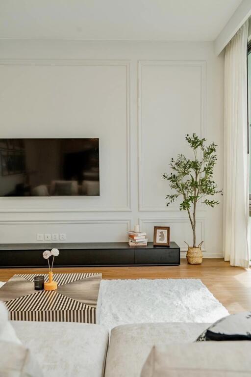 Modern living room with wall-mounted TV, decor items, and a potted plant