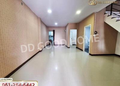 spacious empty living room with tiled floor, stairs to an upper level, and a view towards other rooms and possibly a kitchen