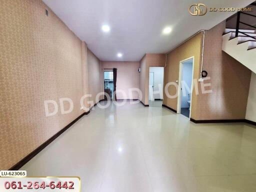 spacious empty living room with tiled floor, stairs to an upper level, and a view towards other rooms and possibly a kitchen