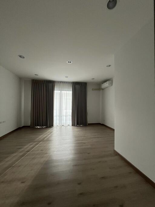 Spacious and empty living room with large windows and curtains