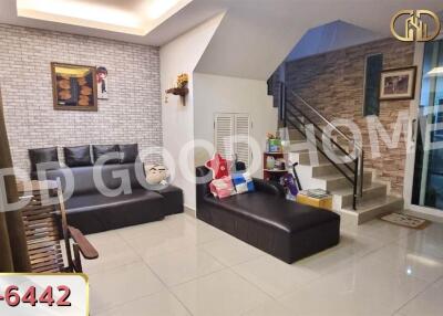 Modern living room with a black leather sofa and brick accent wall