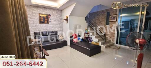 Modern living room with a black leather sofa and brick accent wall