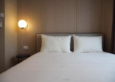 A well-lit modern bedroom with a double bed and pillows