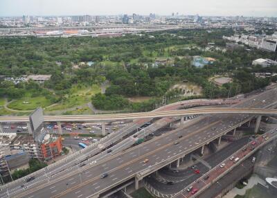 Aerial view of a highway and green park with city skyline in the background