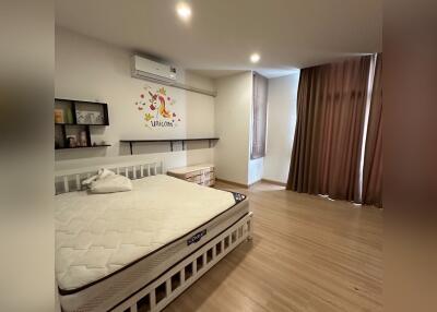 Spacious and well-lit bedroom with a large bed and wooden flooring