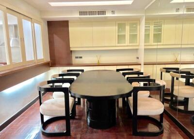 Modern dining area with a large table and chairs, mirrored wall, and ample cabinet space.