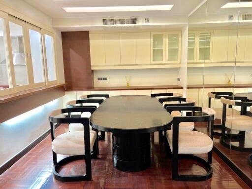 Modern dining area with a large table and chairs, mirrored wall, and ample cabinet space.