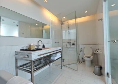 Modern bathroom with glass shower, large mirror, and marble tiles