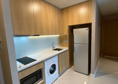 Modern kitchen with wooden cabinets, built-in appliances, and marble flooring.