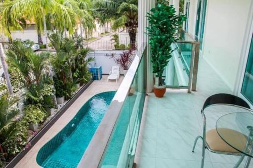 Balcony overlooking pool with lush greenery