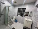 Modern bathroom with glass shower, toilet, sink, and large mirror