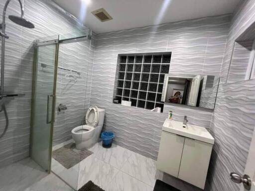 Modern bathroom with glass shower, toilet, sink, and large mirror