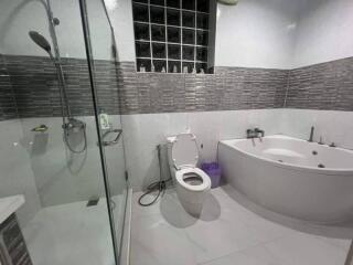 Modern bathroom with glass shower, bathtub, and toilet