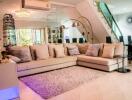 Modern living room with large beige sectional sofa, decorative rug, and open space design