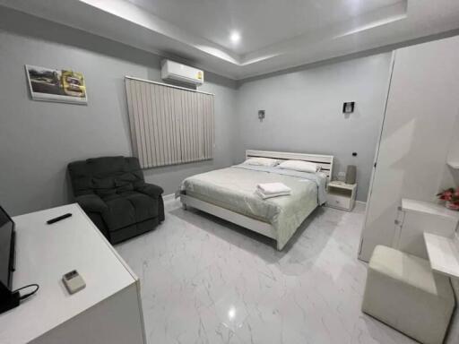 Modern bedroom with bed, recliner, air conditioner, and TV