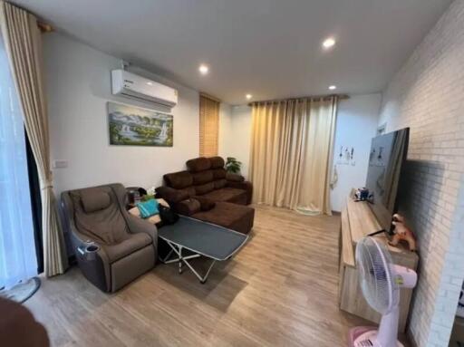 Modern living room with couch, recliner, TV, and air conditioning