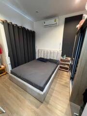 Modern bedroom with bed, black curtains, and a mini-split air conditioner