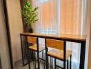 Compact dining area with high table and chairs next to a window