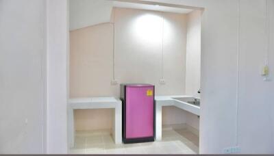 compact kitchen with white counters and pink fridge