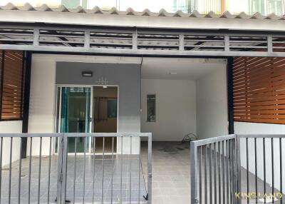 Front view of a residential building with a gated entry and carport area.