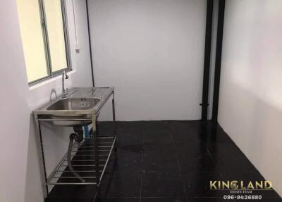 Minimalist kitchen with basic stainless steel sink and black flooring