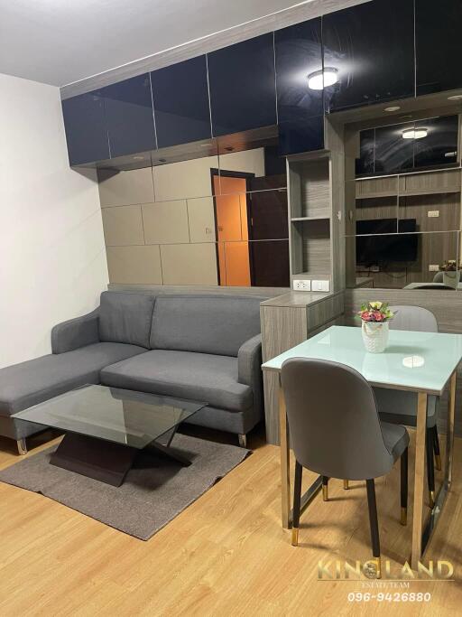 Modern living and dining area with gray sofa, glass coffee table, and a small dining table with chairs