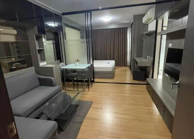 Photo of a modern studio apartment with open-plan living area, dining space, and visible bedroom