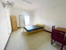 Photo of a simple bedroom with a bed, wardrobe, table, and chairs