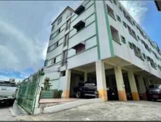 Exterior view of a multi-story residential building with parking area